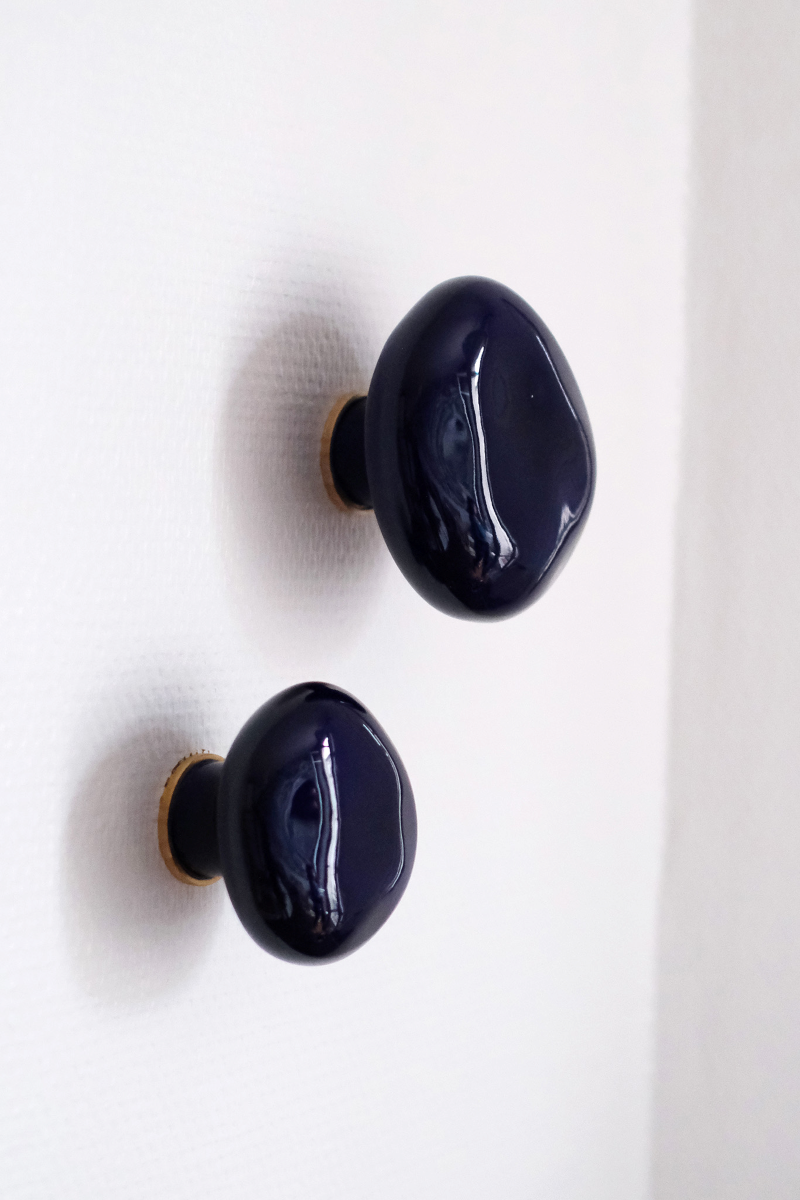 La patère Agate tire son nom de la pierre précieuse éponyme. Les Grecs et les Égyptiens l'utilisaient déjà dans la confection d'objets sacrés. Chaque patère possède sa propre personnalité, accentuée par les émaux cristallisés ou colorés qui s'harmonisent avec sa forme douce et organique, reflétant la diversité des teintes présentes dans les pierres d'Agate.

Son design intemporel et organique évoque la beauté et la simplicité des galets, tandis que sa délicate base est ornée d'une bague en laiton brossé