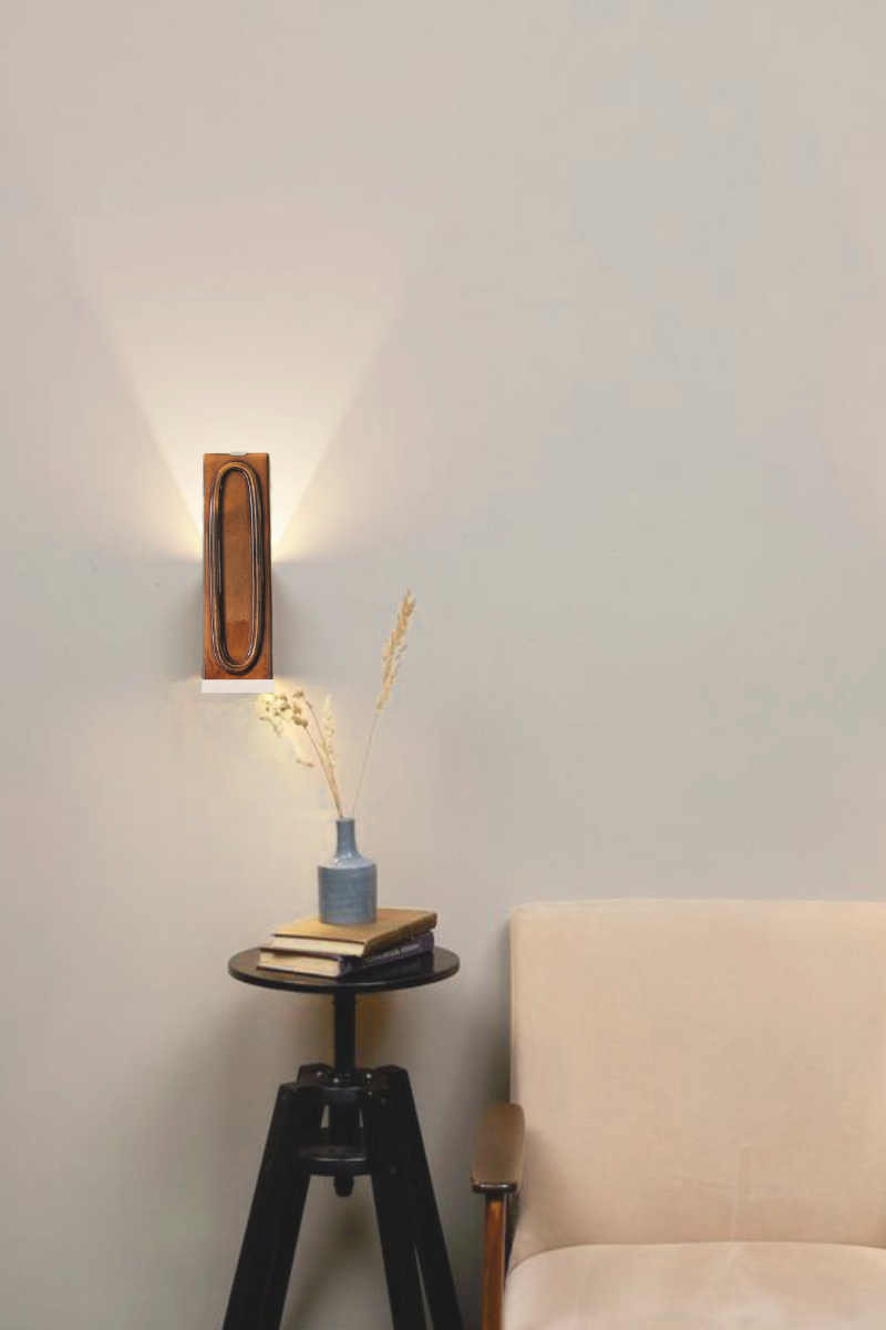 Applique arty porto, couleur marron, dans une ambiance de salon, avec un tabouret bout de canapé noir et un canapé crème. L’applique Arty, imaginée par Coline Leleu et Sébastien Carette, porte bien son nom : elle apporte une touche artistique discrète qui habille le mur avec légèreté. Chaque carreau de céramique est façonné à la main au Portugal, et révèle ses nuances et textures uniques, témoignant du geste de l’artisan.