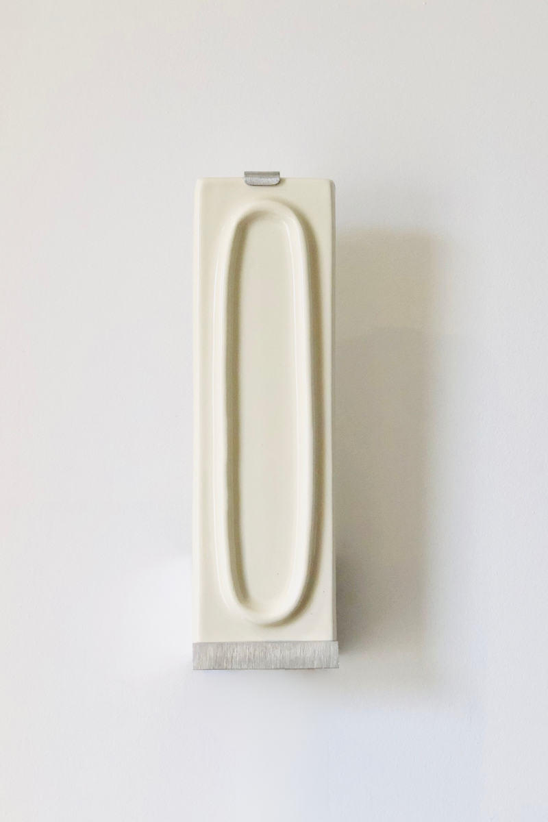 Zoom sur l'applique arty branco. L’applique Arty, imaginée par Coline Leleu et Sébastien Carette, porte bien son nom : elle apporte une touche artistique discrète qui habille le mur avec légèreté. Chaque carreau de céramique est façonné à la main au Portugal, et révèle ses nuances et textures uniques, témoignant du geste de l’artisan.