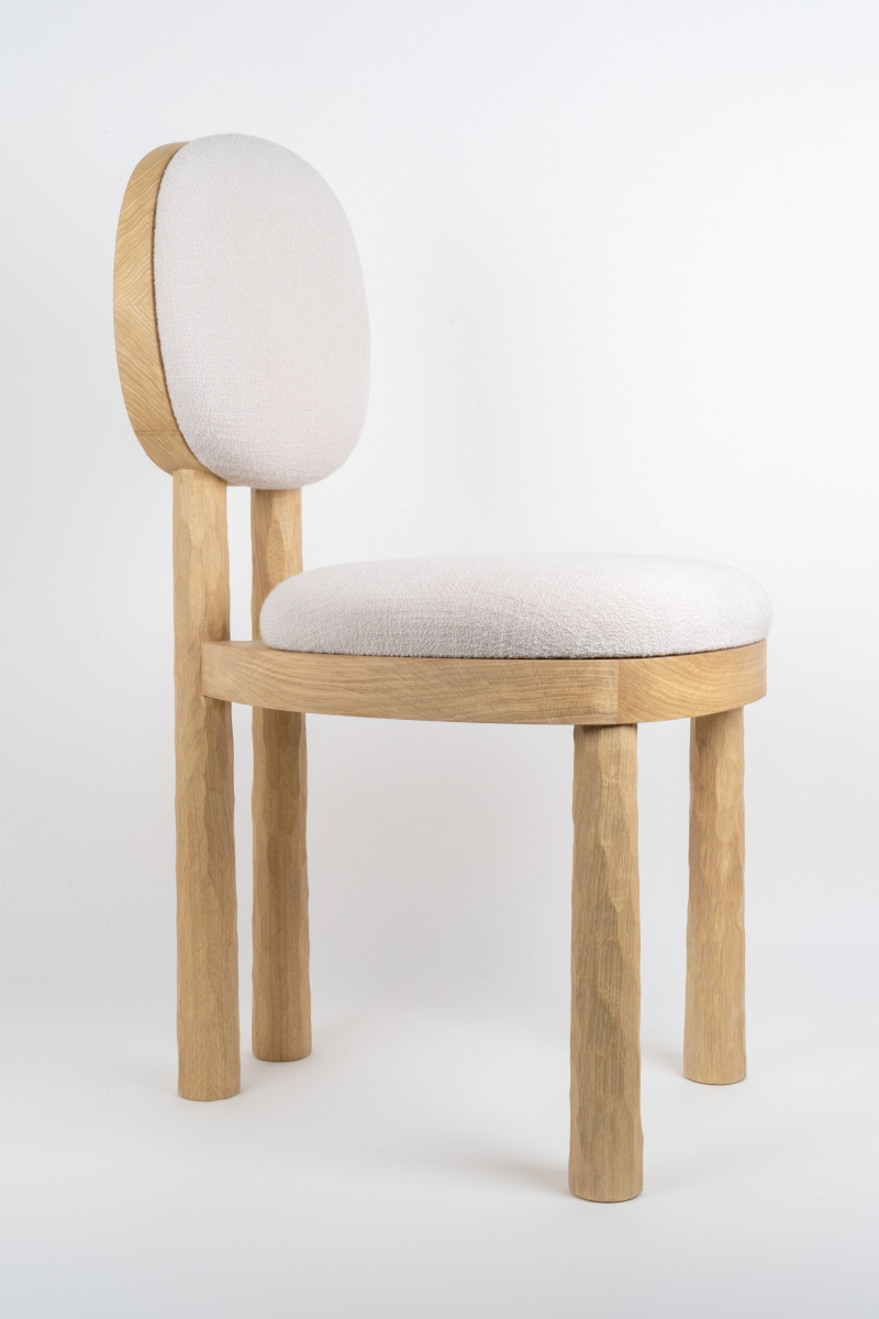 La chaise 39U, conçue par le designer Henri Canivez, évoque une harmonie subtile entre tradition et modernité. Réalisée en chêne clair, sa texture gougée témoigne du travail artisanal des meilleurs ébénistes parisiens. Les coussins d'assise et de dossier, délicatement arrondis, invitent à la détente avec une générosité et douceur, créant ainsi un contraste apaisant avec la robustesse du bois. Cette pièce, discrète et élégante, raconte une histoire à travers ses lignes assumées et son confort accueillant.