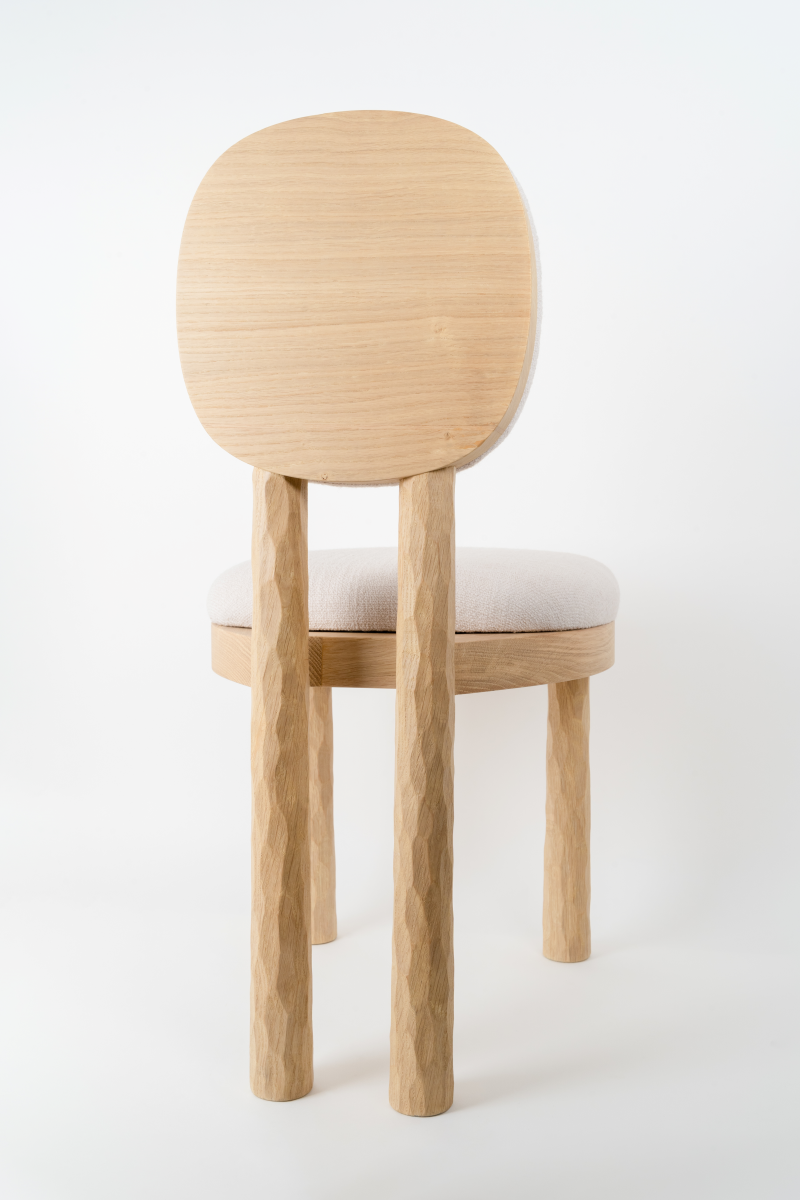 La chaise 39U, conçue par le designer Henri Canivez, évoque une harmonie subtile entre tradition et modernité. Réalisée en chêne clair, sa texture gougée témoigne du travail artisanal des meilleurs ébénistes parisiens. Les coussins d'assise et de dossier, délicatement arrondis, invitent à la détente avec une générosité et douceur, créant ainsi un contraste apaisant avec la robustesse du bois. Cette pièce, discrète et élégante, raconte une histoire à travers ses lignes assumées et son confort accueillant.