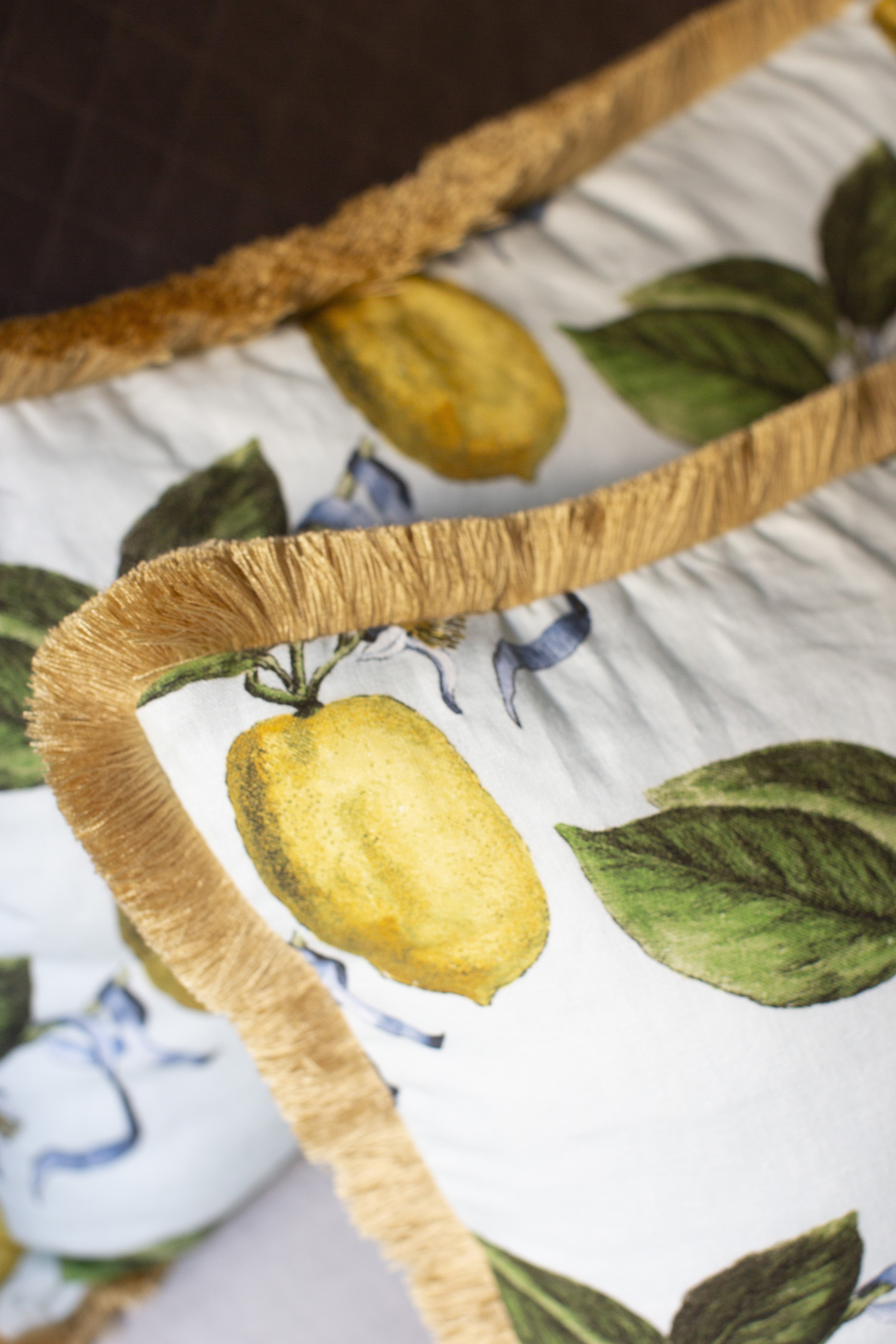 Ce coussin s’impose comme une pièce de caractère au sein de la collection Caroline Andreoni La Maison. Son imprimé citrus, à la fois lumineux et vitaminé, évoque la douceur d’un jardin méditerranéen et insuffle instantanément énergie et vitalité à votre intérieur. Le passepoil doré, discret mais élégant, souligne les contours du coussin avec finesse et capte la lumière pour un effet subtilement précieux.
