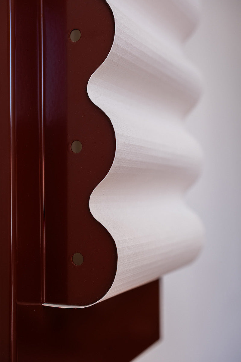 Les appliques Frame Alu Brun de Violaine d'Harcourt sont fabriquées à la main au Portugal, en aluminium laqué brun-rouge et papier.  Dotées d'un design minimaliste et rendant un subtil hommage à l'architecture moderne, les appliques murales Frame sont réalisées avec des matériaux contrastés qui rehaussent le toucher doux d'une vague de papier.