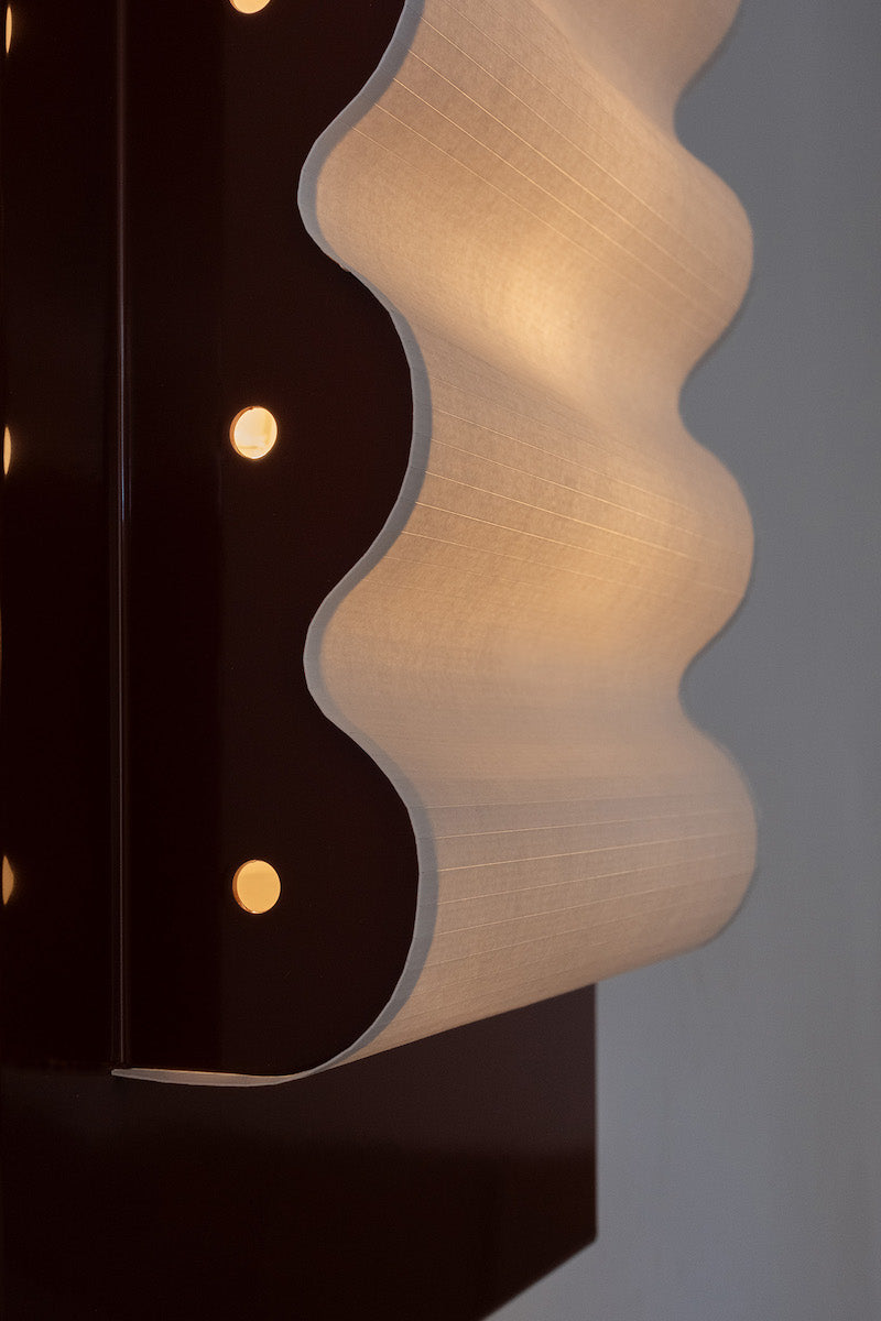 Les appliques Frame Alu Brun de Violaine d'Harcourt sont fabriquées à la main au Portugal, en aluminium laqué brun-rouge et papier.  Dotées d'un design minimaliste et rendant un subtil hommage à l'architecture moderne, les appliques murales Frame sont réalisées avec des matériaux contrastés qui rehaussent le toucher doux d'une vague de papier.