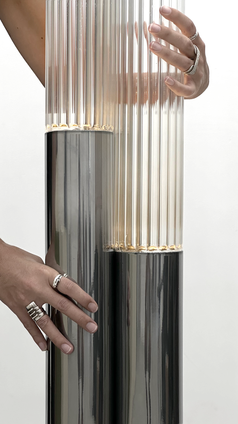 La rencontre de Mickaël avec un artisan verrier lui permet de retranscrire toutes les nuances d'oscillations et de reflets auxquels le paysage méditerranéen l'a habitué. Des cannes striées, fumées ou transparentes assemblées sous la forme d'un cactus élancé et raffiné, qui révèlent toute leur singularité en s'éclairant.  Tous les reliefs du verre sont projetés sur l'environnement qui l'entoure. Une ode au territoire d'origine de Mickaël.