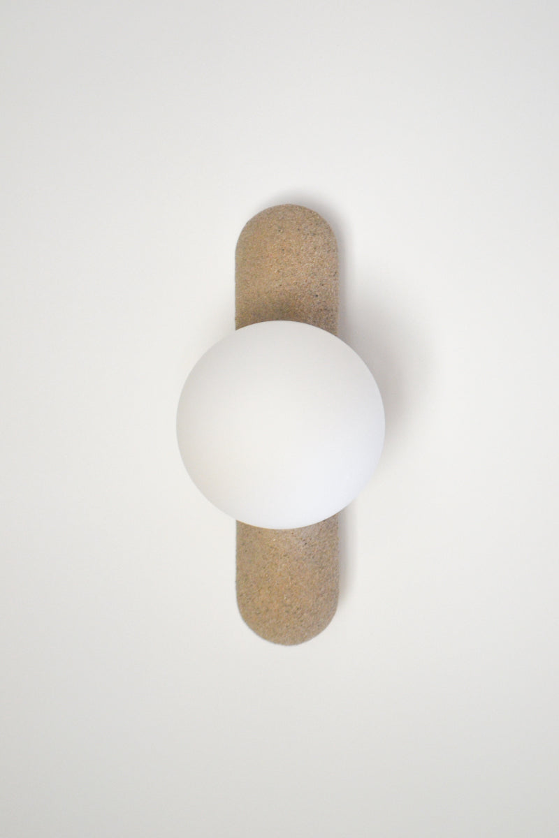 Intrigué par le figuier de barbarie qui se révèle être un outil naturel luttant contre l'érosion des sols, et participant à la préservation du territoire, Mickaël s'en inspire pour dessiner cette lampe. Volupté et douceur, sont les maîtres mots pour célébrer cette plante.  Modelée à partir de la terre que le figuier protège, l'applique Figue de Barbarie naît en terre cuite par la main du designer. Les opalines comme des baies charnues rayonnent, et mettent en lumière cette prouesse naturelle.