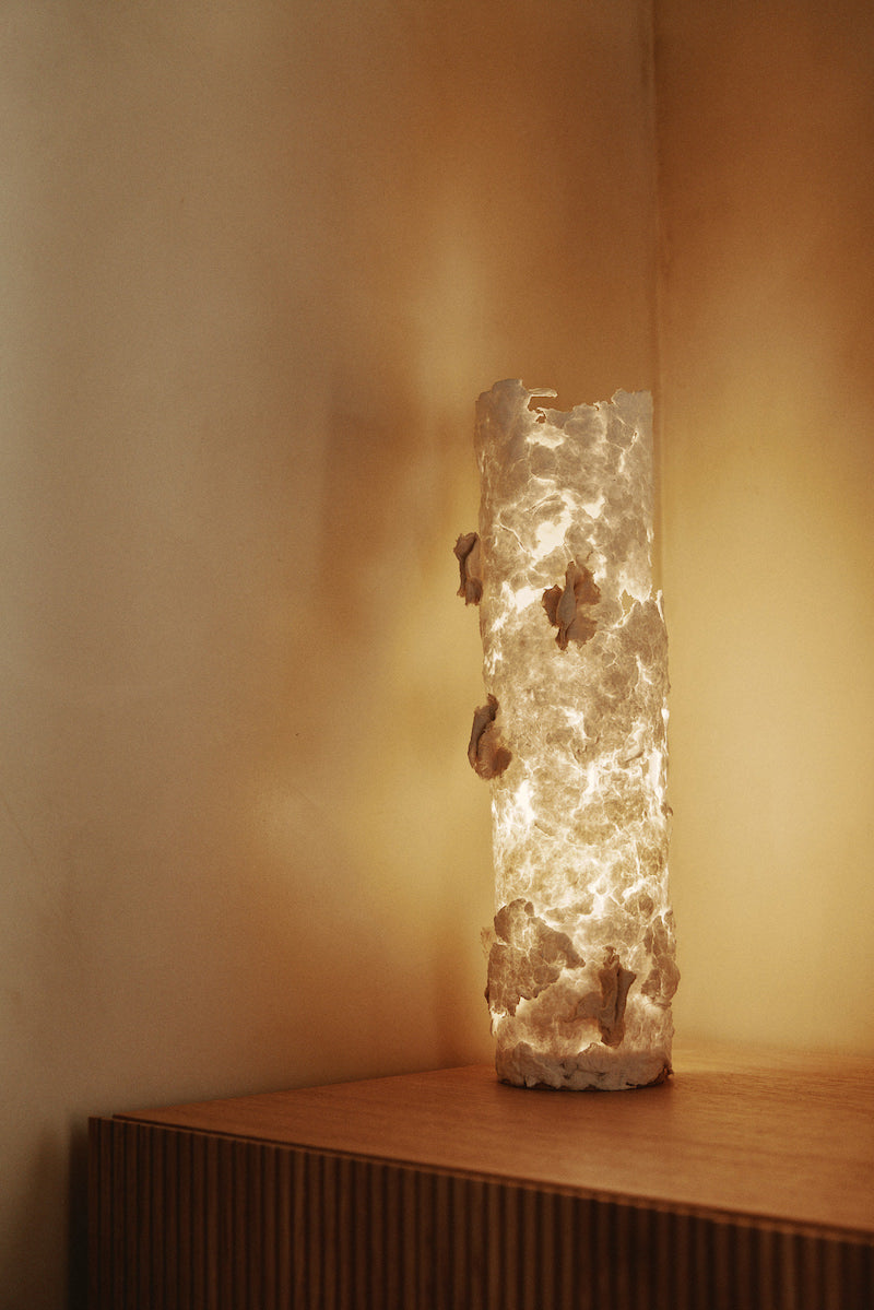 La lampe à poser grand modèle Abaca est soigneusement créée avec amour et délicatesse par l’artiste Emma Karila. Offrant une ambiance chaleureuse à votre intérieur, la lampe en papier allie l’artisanat et la tradition à un esthétique moderne et élégant.  Avec sa structure en métal, cette pièce apportera un côté artistique à votre décoration.  Fabriquée à partir de papier coton abaca, puis sculptée mouillée, en séchant, cette lampe est unique en son genre rendant chaque exemplaire en véritable œuvre d’art.