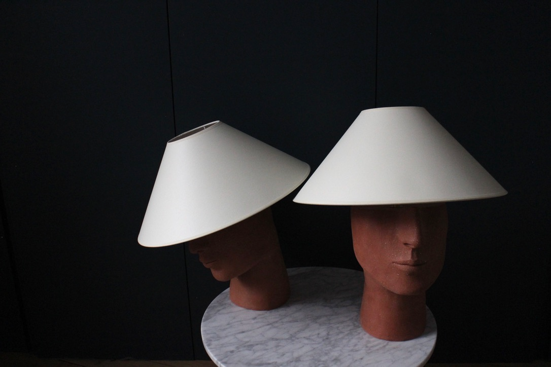 Fabriquée à base de grès orange brut chamotté, la lampe à poser Timide reprend un visage affirmé. Cette pièce fait partie du duo de lampes "Les Sœurs" proposé par l'artiste Thalia Dalecky.