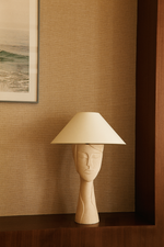 Table lamp Tranquille by Thalia Dalecky, in raw white stoneware engraved in bas-relief. A serene face emerges from the unglazed surface, still, stately, as though carved from stone.