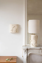 L'applique Cactus, inspirée des esquisses de la créatrice Adeline Delesalle, joue sur des formes en relief reprenant des représentations abstraites de cactus. Alliant sa profondeur à un jeu d'ombre et de lumière, l'applique est fabriquée avec du grès blanc chamotté, terre lisse à laquelle a été rajoutée de la terre cuite broyée, lui donnant une texture idéale pour le modelage et un grain authentique.