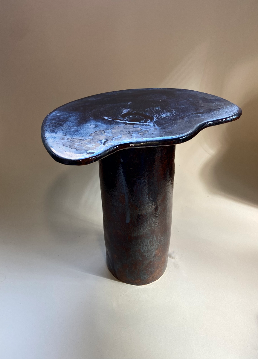 Petite table d'appoint Tempête au design épuré réalisé en céramique à effets métallisés sur le plateau et noir. Cette pièce, réalisée par l'artiste Thalia Dalecky, présente des ornages sur le pied.