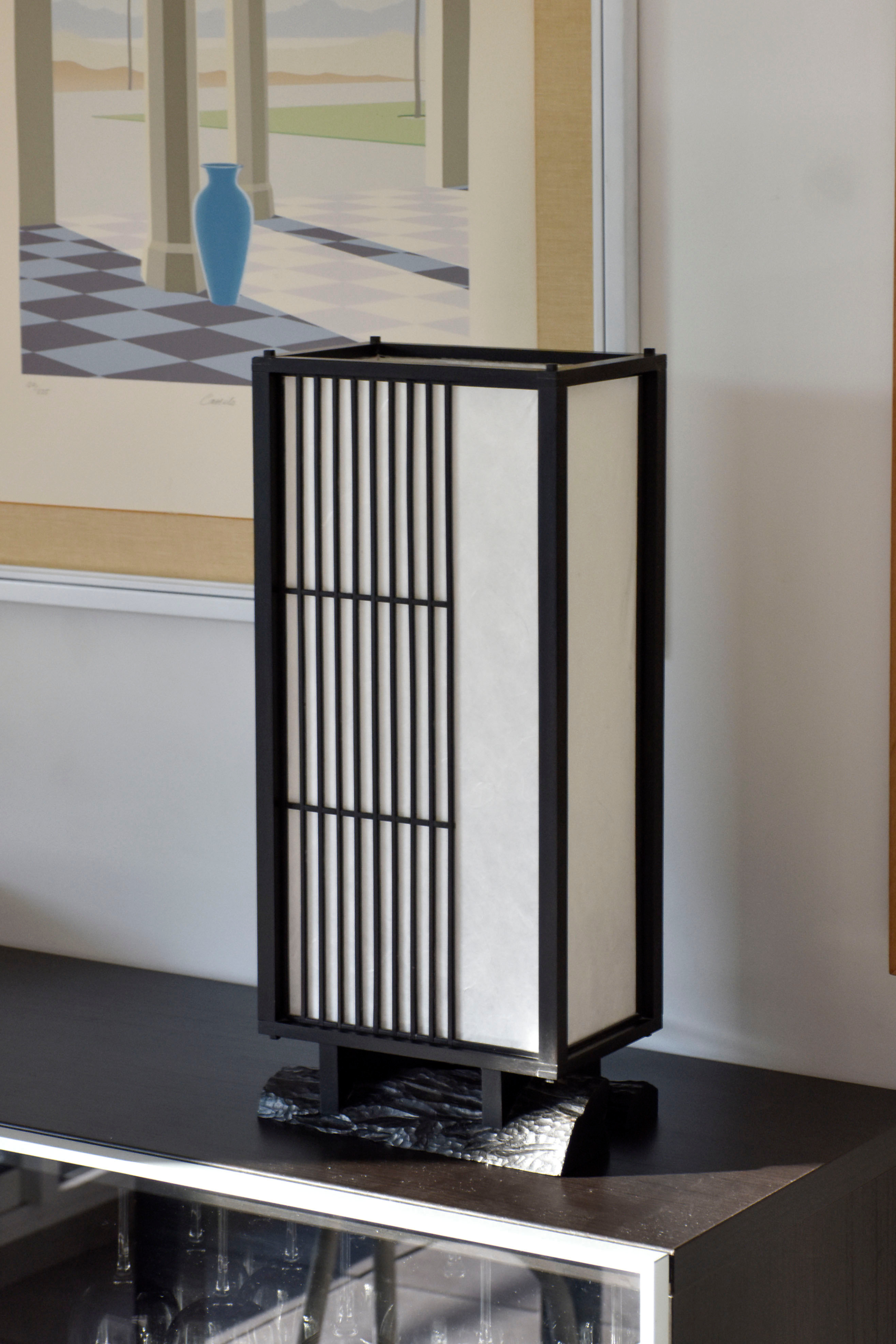 Véritable héritage de la culture japonaise traditionnelle, cette lampe puise son inspiration dans l’équilibre entre rigueur et douceur. Imaginée par le designer Thomas Coup La Fronde, elle associe la précision des savoir-faire artisanaux aux courbes organiques d’un pied en ébène massif. Les assemblages, subtilement révélés, témoignent d’une exigence rare tout en préservant une esthétique épurée et intemporelle.