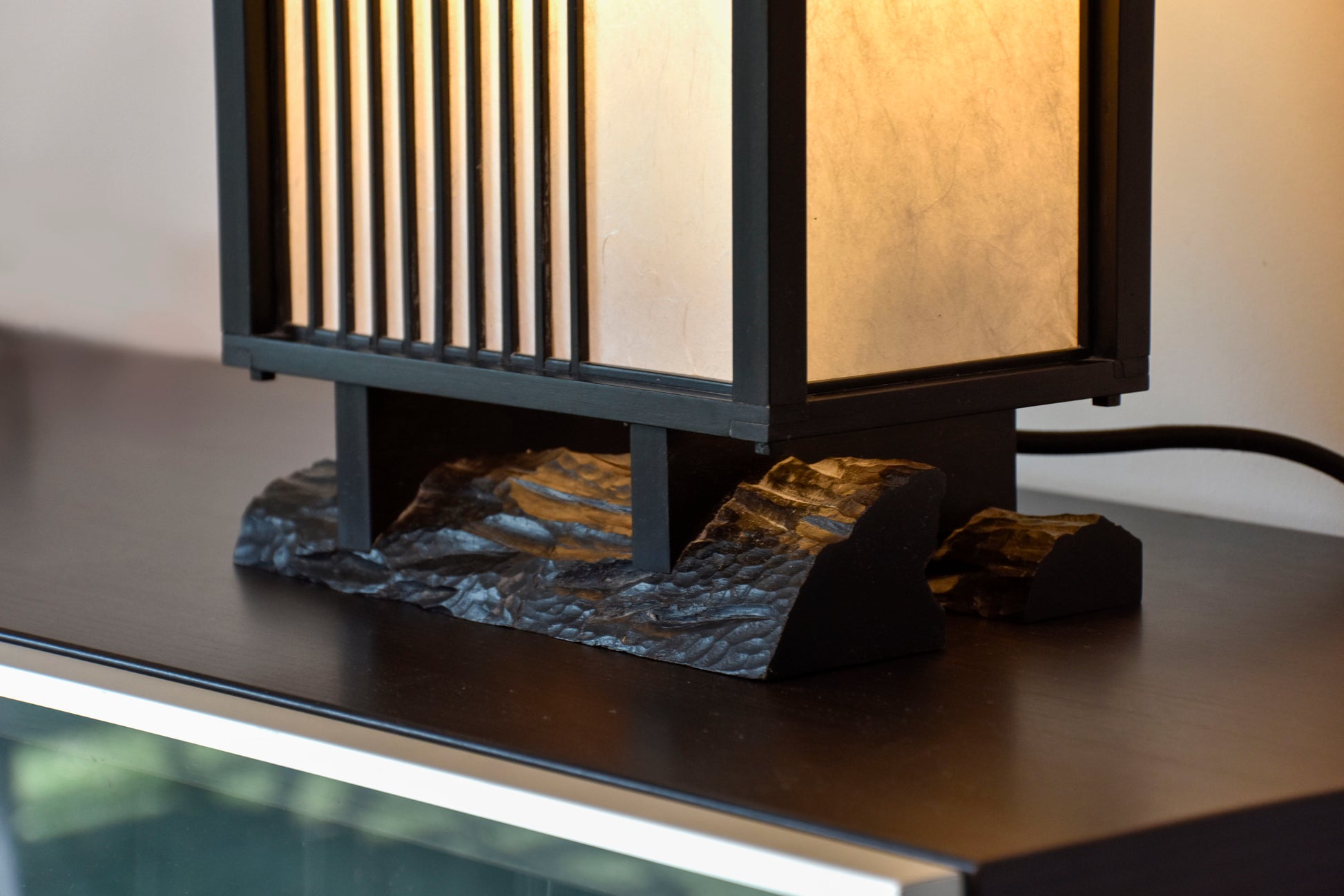 Véritable héritage de la culture japonaise traditionnelle, cette lampe puise son inspiration dans l’équilibre entre rigueur et douceur. Imaginée par le designer Thomas Coup La Fronde, elle associe la précision des savoir-faire artisanaux aux courbes organiques d’un pied en ébène massif. Les assemblages, subtilement révélés, témoignent d’une exigence rare tout en préservant une esthétique épurée et intemporelle.