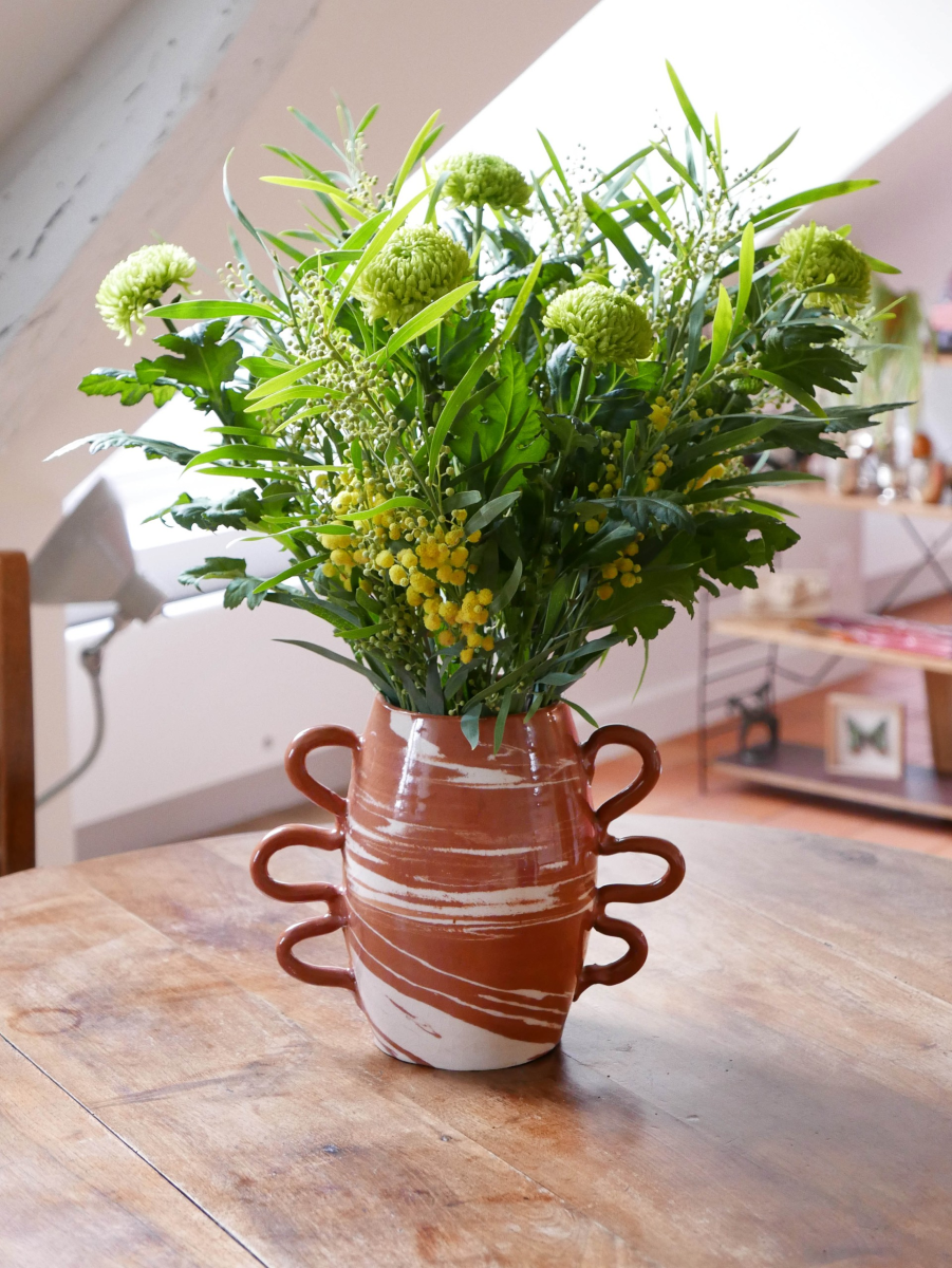 Ces objets en faïence émaillée sont entièrement façonnés à la main par un artisan potier marocain travaillant dans l’Atlas. Gardien d’une tradition séculaire, il a repris l’atelier familial et perpétue un savoir-faire précieux. Les objets sont tournés un par un à la main en utilisant la technique des terres mêlées. Il s’agit de mélanger des argiles blanches et rouges afin de créer des motifs aléatoires marbrés ou zébrés dans des teintes naturelles terracotta. Chacun de ces objets est ainsi totalement unique