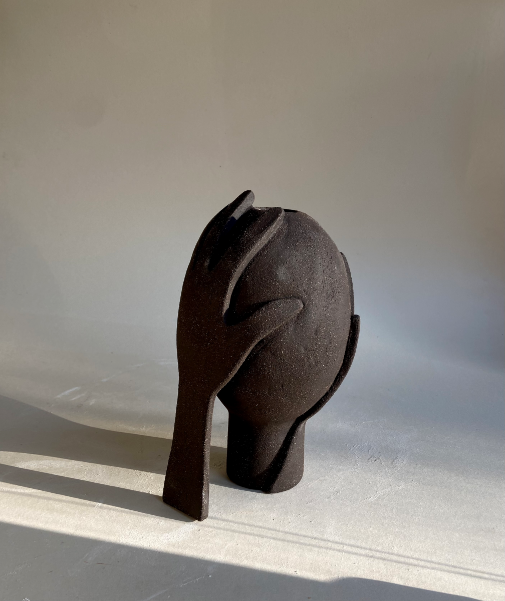 Vase Je te protège by Thalia Dalecky, in raw black stoneware from the « À mains nues » collection. The enveloping form carries the gesture of protection, ceramic as sheltering skin.
