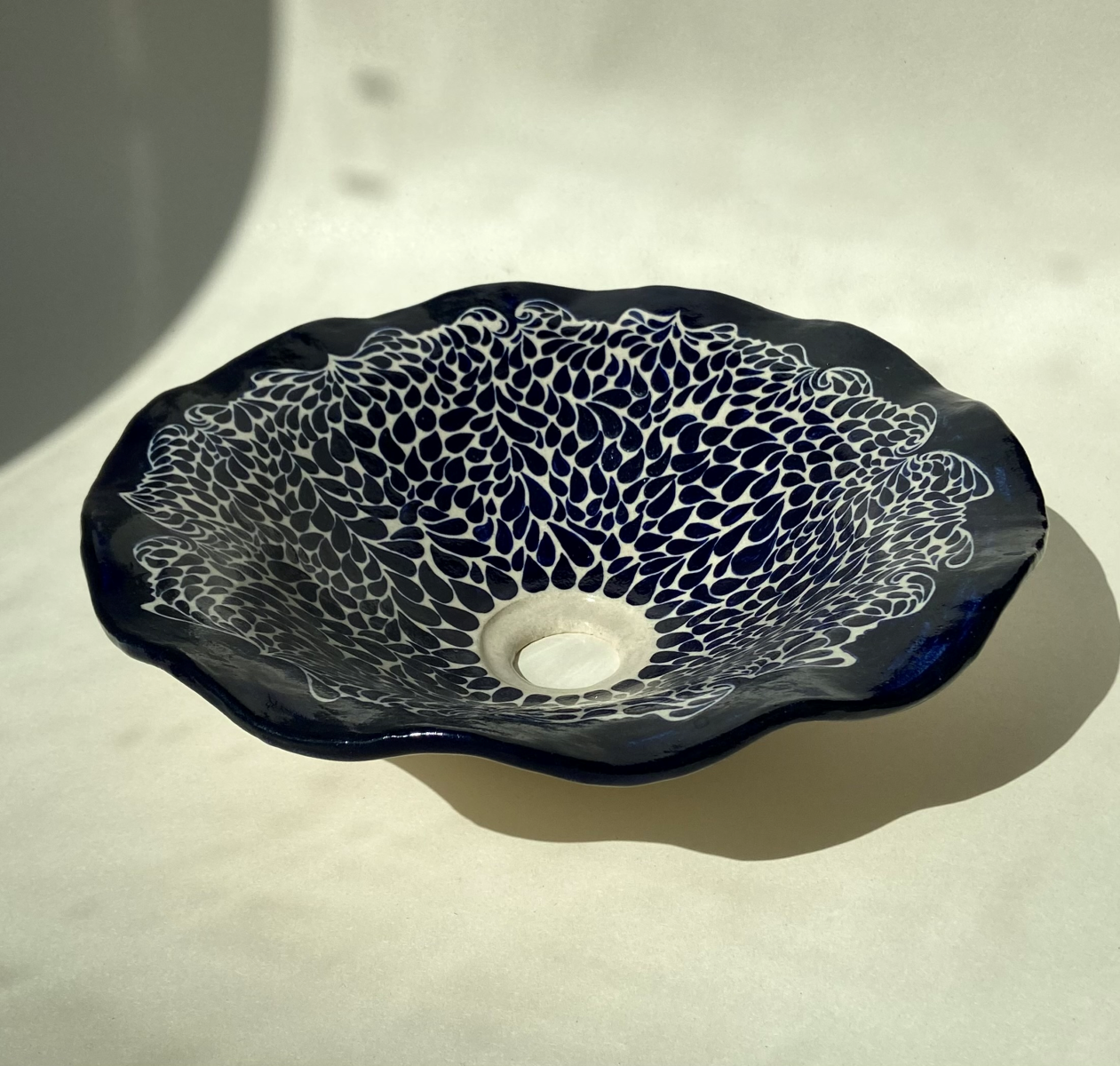 Basin Acqua by Thalia Dalecky, in white stoneware hand-painted in midnight blue. The artist's aquatic motifs evoke water droplets in a silent dance across the glazed ceramic surface.