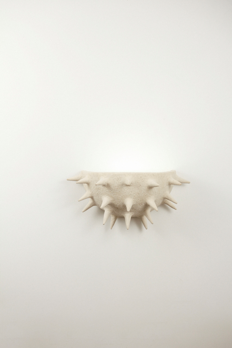 Cette applique Jupiter constituée de grès chamotte présente une texture avec des grains de sable. Chaque pièce est unique, numérotée, signée et modelée manuellement dans un grès chamotte, une argile cuite plusieurs fois entre 900 et 1400 degrés. Au cours de ce processus, l'objet devient aussi solide que la pierre. C'est par l'assemblage, le modelage, la sculpture et les différentes cuissons que l'objet se révèle.

Grâce à la céramique, Alan Louis capture l'essence particulière de l'élégance brute.