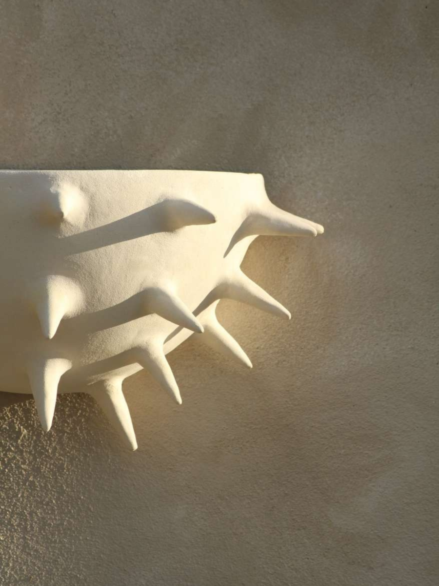 Cette applique Jupiter constituée de grès chamotte présente une texture avec des grains de sable. Chaque pièce est unique, numérotée, signée et modelée manuellement dans un grès chamotte, une argile cuite plusieurs fois entre 900 et 1400 degrés. Au cours de ce processus, l'objet devient aussi solide que la pierre. C'est par l'assemblage, le modelage, la sculpture et les différentes cuissons que l'objet se révèle.

Grâce à la céramique, Alan Louis capture l'essence particulière de l'élégance brute.