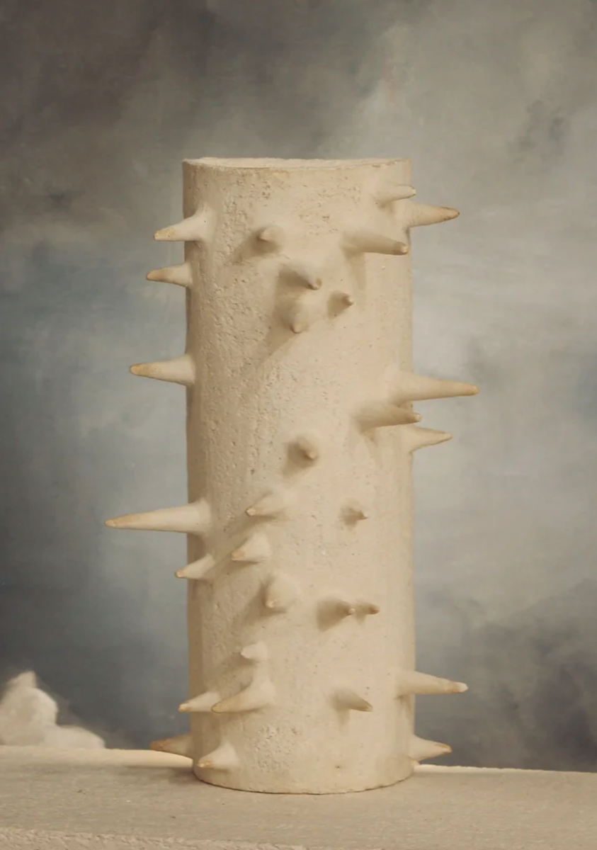 Cette applique Ostentus constituée de grès chamotte présente une texture avec des grains de sable.&nbsp;Chaque pièce est unique, numérotée, signée et modelée manuellement dans un grès chamotte, une argile cuite plusieurs fois entre 900 et 1400 degrés.

Grâce à la céramique, Alan Louis capture l’essence particulière de l’élégance brute et naturelle.