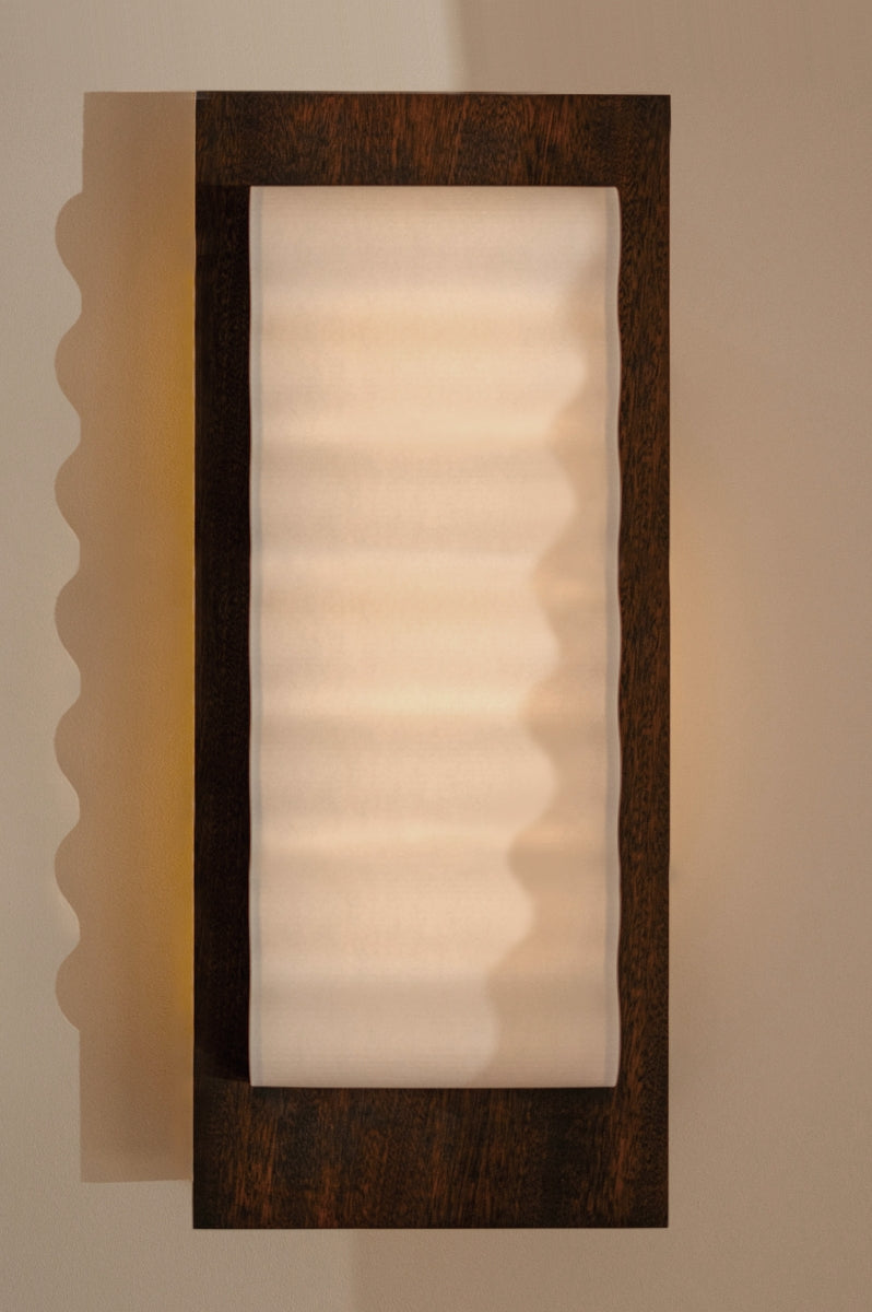 Les appliques Frame Wood de Violaine d'Harcourt sont fabriquées à la main au Portugal avec du bois d'acajou huilé et du papier.

Dotées d'un design minimaliste et rendant un subtil hommage à l'architecture moderne, les appliques murales Frame sont réalisées avec des matériaux contrastés qui rehaussent le toucher doux d'une vague de papier.
