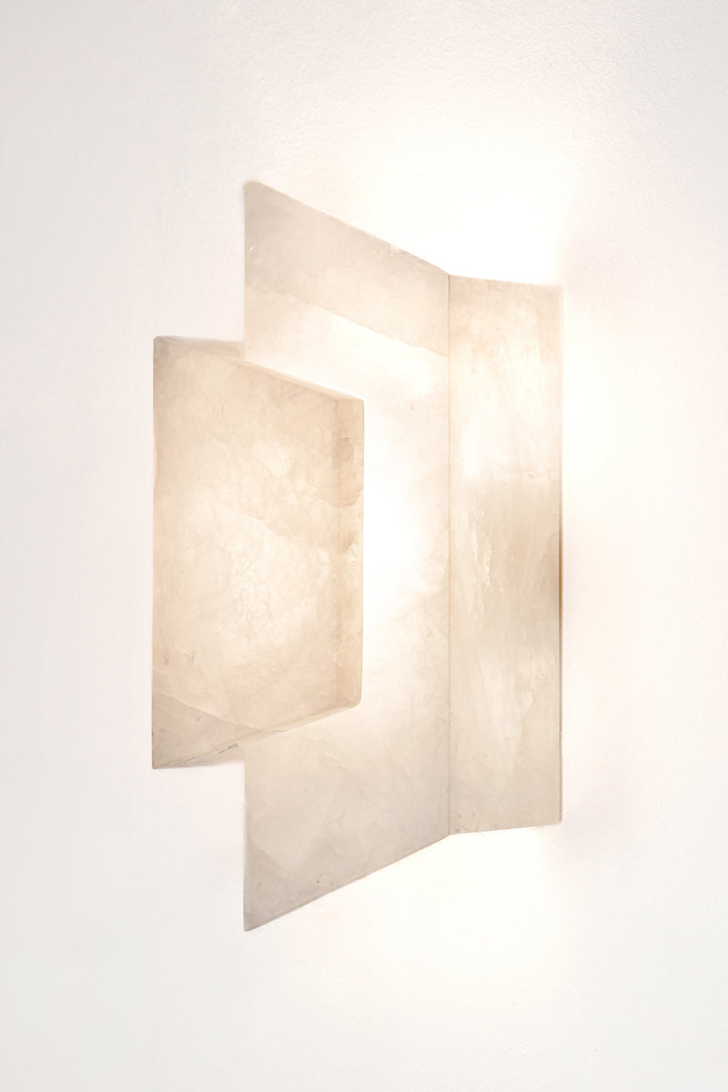 Applique Enveloppée en golden quartzite et laiton est Inspirée de l’art du pliage et des formes enveloppantes de l’origami japonais. Enveloppée joue sur un équilibre délicat entre puissance minérale et apparente légèreté. La pierre, traversée par la lumière, évoque la finesse des papiers de soie et de riz utilisés dans les lanternes asiatiques traditionnelles.