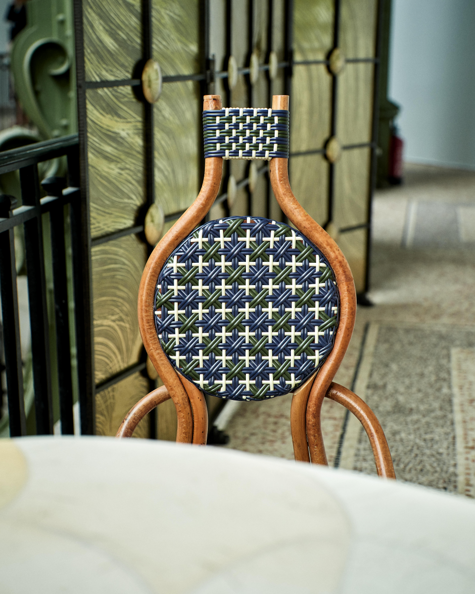 La chaise Odette fait la part belle au rotin. Le Second Empire a vu se développer le métier de rotinier et a été l’âge d’or de ce matériau. Le rotin est une tige de palmier importée des forêts tropicales asiatiques à l’époque coloniale. La chaise de bistro en rotin symbolise à elle seule les terrasses parisiennes et la gaieté de la capitale française. La forme florale et l’utilisation de matières végétales pour le design de la chaise Odette est une référence au catleya.