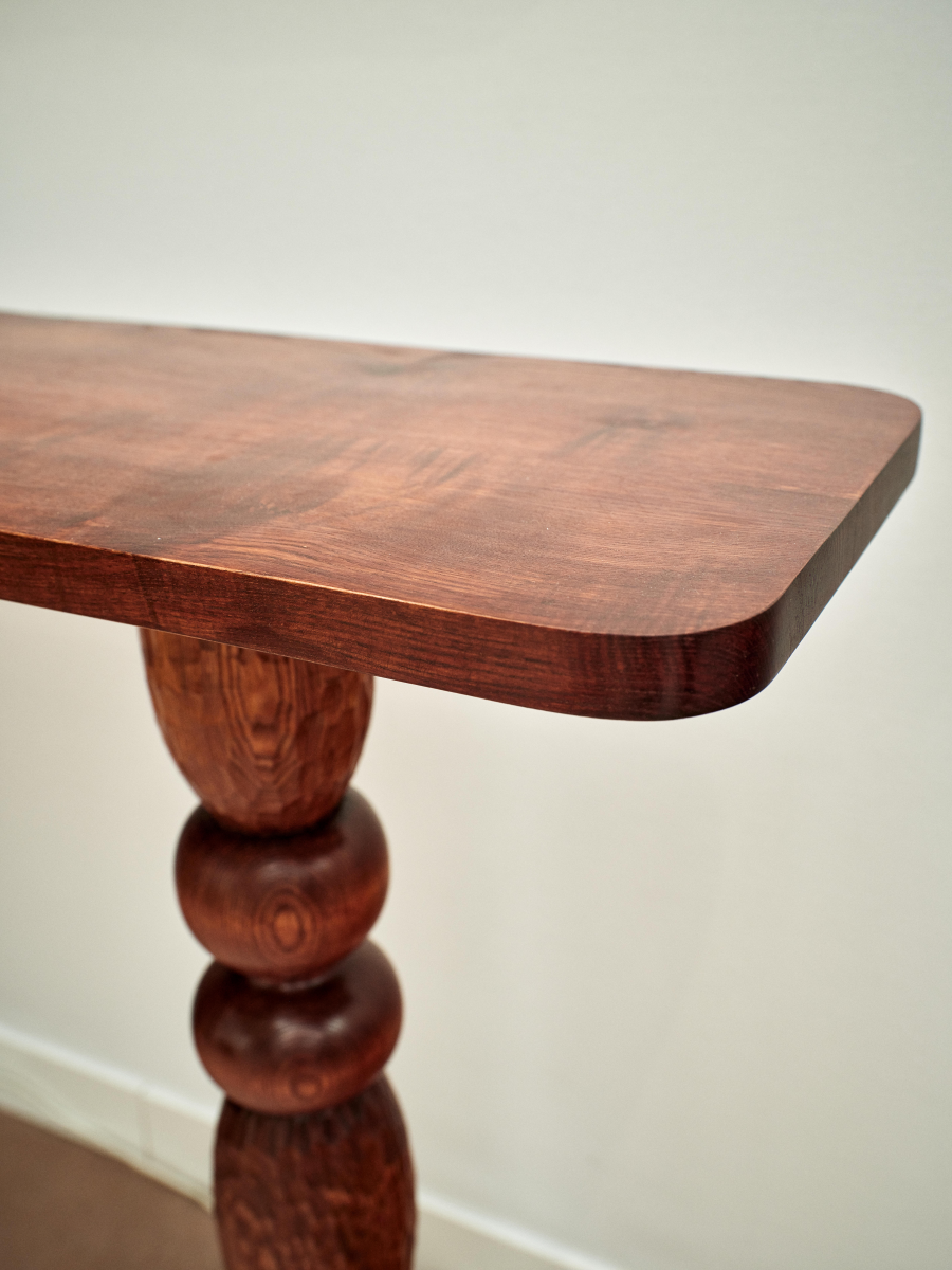 Imaginée en exclusivité pour Caroline Andréoni, la console Volterra explore le dialogue subtil entre équilibre et mouvement. Travaillée comme une sculpture fonctionnelle, elle joue sur l'asymétrie de ses appuis, mêlant force et légèreté dans un même élan.
Le bois, laissé volontairement expressif, révèle sous la main ses veines, ses nœuds et ses nuances, invitant à une lecture tactile de la matière. Chaque détail, du galbe des pieds à la finesse du plateau, célèbre l'imperfection vivante du matériau.