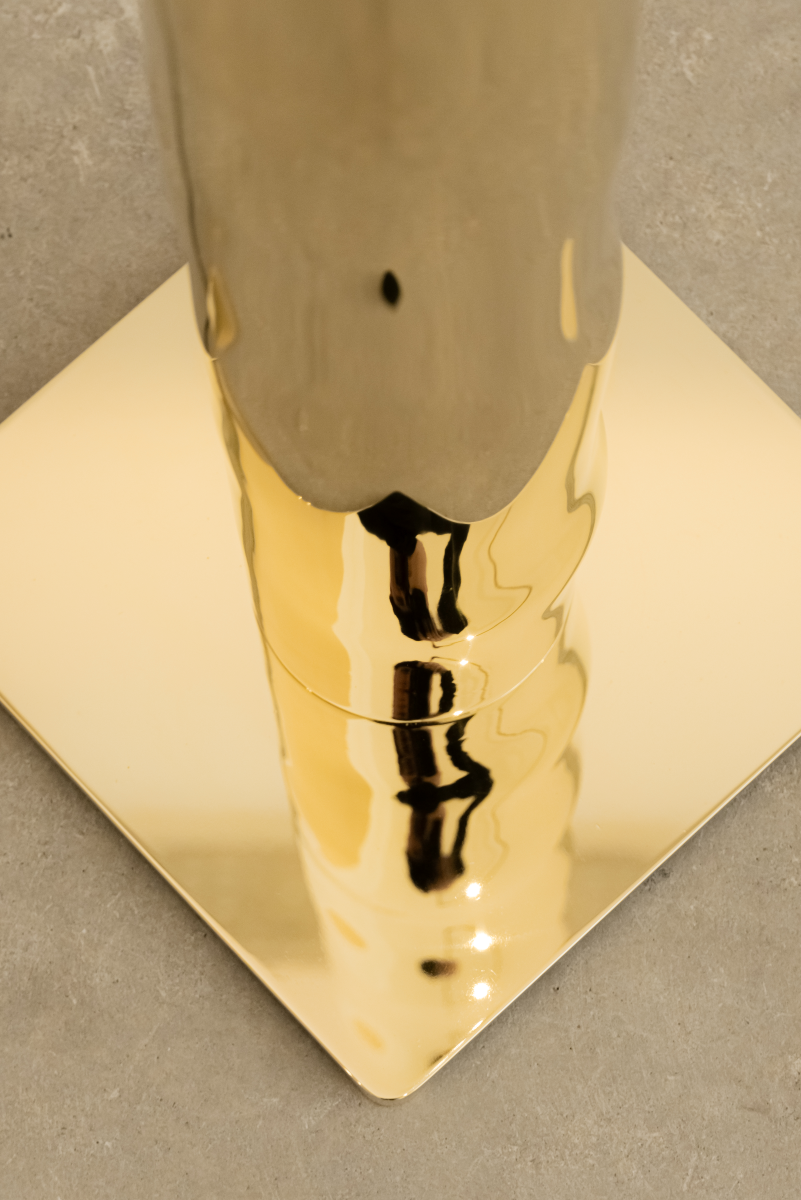 Hélios est un lampadaire sculptural en laiton poli miroir, non verni. Sa source lumineuse, dissimulée, diffuse une lumière douce vers le haut. Entièrement formée, soudée et polie à la main, chaque pièces de cette série sont uniques. Le reflet de sa hauteur dans son socle crée une illusion de mouvement, d’infini, un jeu de perceptions où le vertige s’invite. Hélios transforme l’espace, oscillant entre objet fonctionnel et œuvre sculpturale.