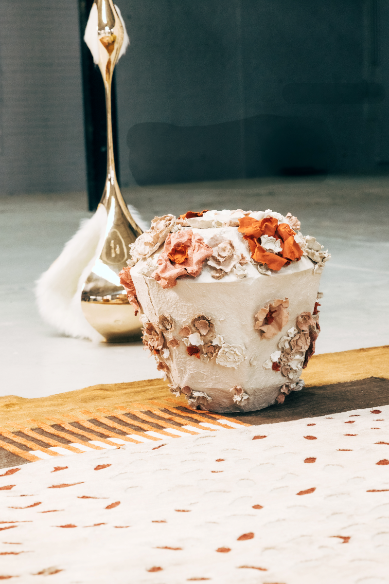 Pour cette lampe à poser Eclosion, Emma Karila utilise une technique de modelage où chaque détail est façonné à la main avec soin. La structure de base est recouverte d’une pâte de papier, ce qui lui donne cette texture un peu rugueuse, presque minérale.

Les fleurs sont créées une par une, avec différentes épaisseurs et couleurs, puis fixées sur la lampe. Cela donne un effet vraiment naturel et organique.