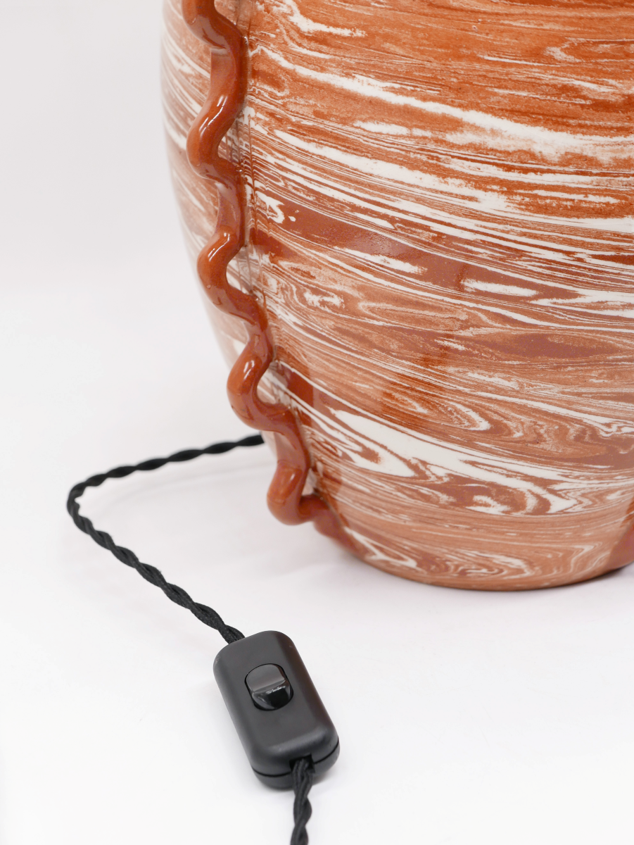 Fruit d’une rencontre entre Datcha et Caroline Andréoni La Maison, la lampe "Kassabah" incarne l’équilibre parfait entre savoir-faire ancestral et design contemporain.

Entièrement façonnée à la main dans les ateliers de potiers marocains, chaque pièce est unique. Le pied en faïence émaillée, réalisé selon la technique des terres mêlées, dévoile un marbré naturel aux nuances terracotta et ivoire. Les anses organiques en relief accentuent son caractère sculptural.