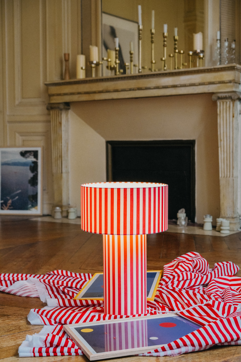Table lamp Octaveo Rouge in white-and-red striped cotton by My Leone. Handmade by Marine and her mother in the Vannes atelier. The tube lampshade becomes the base, bold and artisanal.
