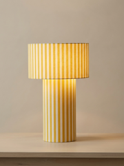 Lampe à poser Octaveo Jaune en tissu coton rayé jaune et blanc par My Leone. Fabriquée à la main par Marine et sa mère à Vannes. L’abat-jour tube devient pied de lampe, une touche solaire.