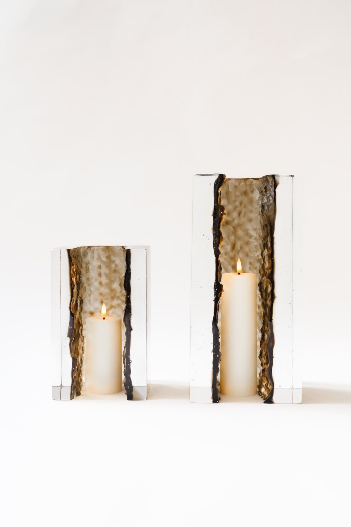 Bougeoir Géoda, réalisé en collaboration avec le verrier Matthieu Gicquel, née d’un dialogue entre matière, lumière et savoir-faire verrier. Inspirée des géodes naturelles, elle explore cette idée de beauté cachée, révélée au cœur de la matière.
À travers un verre travaillé en épaisseur, la collection retranscrit une dualité entre force minérale et délicatesse lumineuse. La matière joue avec la lumière, la capte, la filtre et la diffuse, créant des profondeurs, des reflets et des transparences qui évoluent 