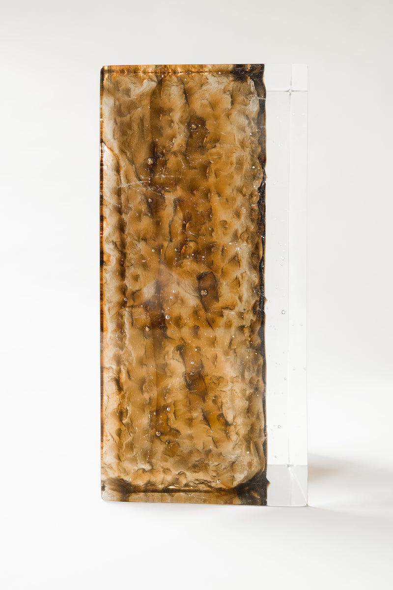 Bougeoir Géoda, réalisé en collaboration avec le verrier Matthieu Gicquel, née d’un dialogue entre matière, lumière et savoir-faire verrier. Inspirée des géodes naturelles, elle explore cette idée de beauté cachée, révélée au cœur de la matière.
À travers un verre travaillé en épaisseur, la collection retranscrit une dualité entre force minérale et délicatesse lumineuse. La matière joue avec la lumière, la capte, la filtre et la diffuse, créant des profondeurs, des reflets et des transparences qui évoluent 