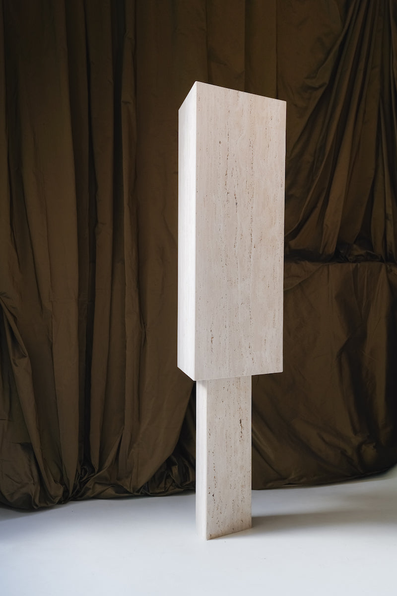 Lampe à poser Lucentia en travertin est née d’une recherche autour de la matière et de la lumière : réussir à faire traverser la lumière à une pierre habituellement perçue comme opaque, pour en révéler une beauté insoupçonnée.
Traversée par la lumière, la matière dévoile alors son paysage intérieur : ses fines aspérités, ses cristallisations, ses microcavités habituellement invisibles. La pierre semble changer de nature, passant d’un matériau dense et minéral à une présence presque vivante et aérienne.