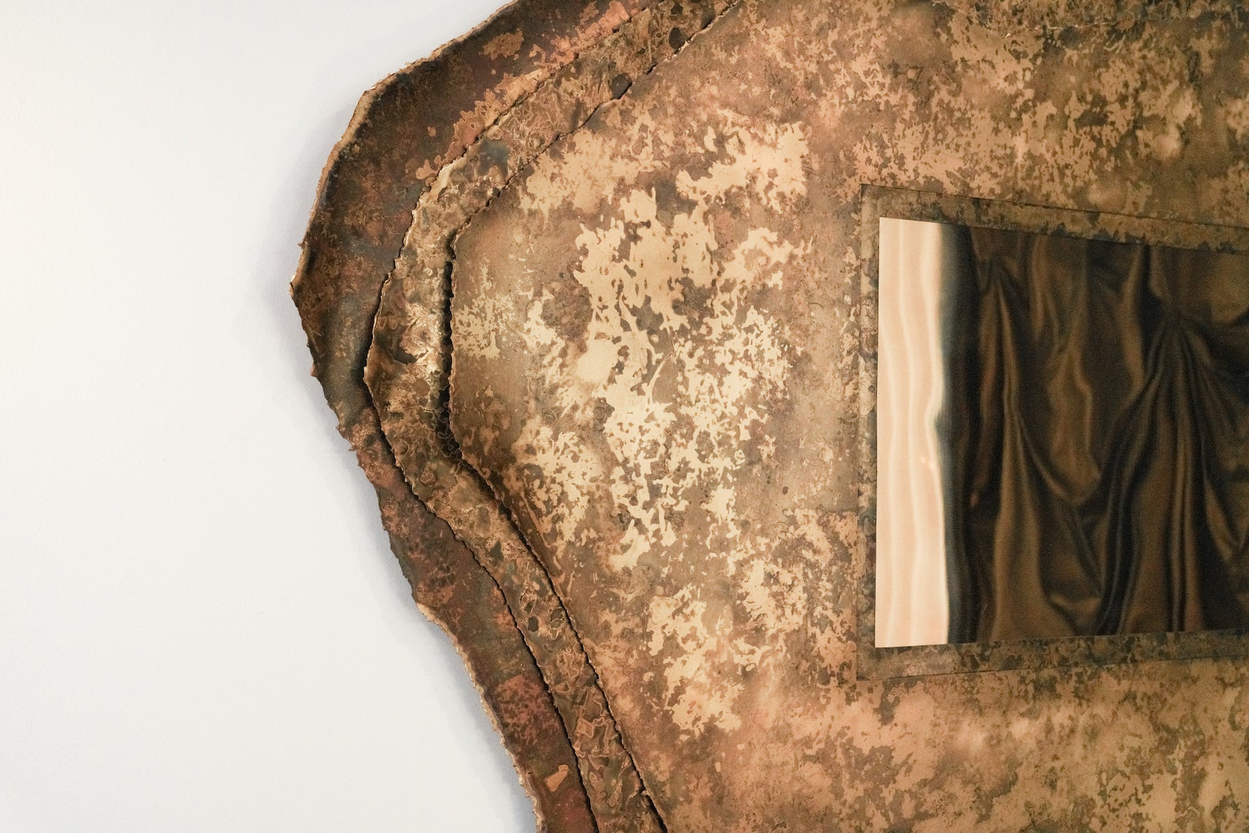 Miroir Chloris en laiton aux patines végétales de Yannick Szekany où le temps et le vivant se lisent dans la texture du métal. Cette pièce est inspirée des feuilles qui jongent le sol en période automnale. Les plantes qui ont servies à son oxydation ont toutes été récoltées dans la forêt de fontainebleau.