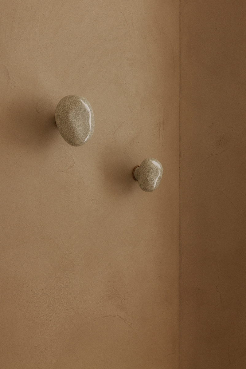 La patère Agate tire son nom de la pierre précieuse éponyme. Chaque patère possède sa propre personnalité, accentuée par les émaux cristallisés ou colorés qui s’harmonisent avec sa forme douce et organique, reflétant la diversité des teintes présentes dans les pierres d’Agate.  Son design intemporel et organique évoque la beauté et la simplicité des galets, tandis que sa délicate base est ornée d’une bague en laiton brossé.