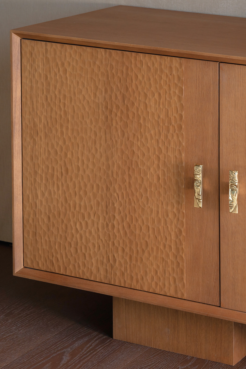 Enfilade en bois plaquée chêne BISCAYNE, imaginée par Caroline Andreoni pour la master bedroom d'une villa privée à Miami. Élégante et intemporelle, cette enfilade en placage chêne séduit par son veinage texturé et ses poignées sculptées en laiton en forme de visage.