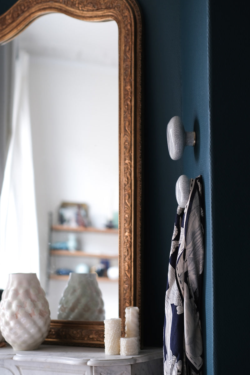 La patère Agate tire son nom de la pierre précieuse éponyme. Chaque patère possède sa propre personnalité, accentuée par les émaux cristallisés ou colorés qui s’harmonisent avec sa forme douce et organique, reflétant la diversité des teintes présentes dans les pierres d’Agate.  Son design intemporel et organique évoque la beauté et la simplicité des galets, tandis que sa délicate base est ornée d’une bague en laiton brossé.