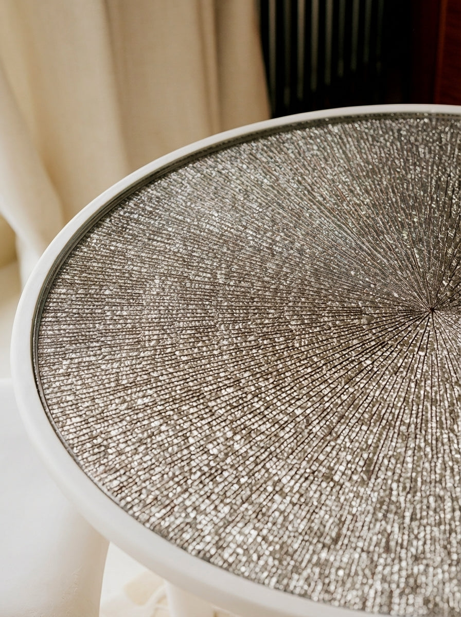 Élégance sculpturale et savoir-faire d’exception s’unissent dans la table d’appoint Bellezza, pièce unique née d’une collaboration entre Caroline Andréoni, Staff Espaces Volumes et Atelier Pictet. Présentée à l’occasion de la Biennale Révélations 2025, elle incarne l’art décoratif contemporain dans toute sa richesse.

Le plateau en verre est magnifié par une gravure en ronde-bosse, buriné avec précision, puis doré à la feuille d’or Moongold, une teinte précieuse aux reflets chauds et lumineux. 