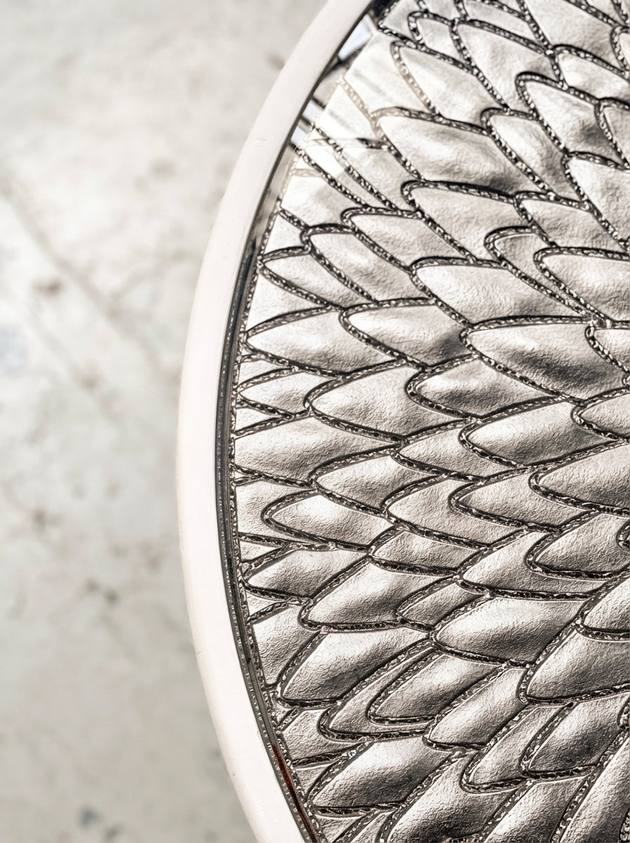 Élégance sculpturale et savoir-faire d’exception s’unissent dans la table d’appoint Bellezza, pièce unique née d’une collaboration entre Caroline Andréoni, Staff Espaces Volumes et Atelier Pictet. Présentée à l’occasion de la Biennale Révélations 2025, elle incarne l’art décoratif contemporain dans toute sa richesse.

Le plateau en verre est magnifié par une gravure en ronde-bosse, buriné avec précision, puis doré à la feuille d’or Moongold, une teinte précieuse aux reflets chauds et lumineux. 