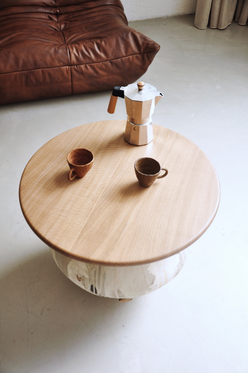Table basse conçue et fabriquée par la céramiste Marguerite Porche. Le large piétement en grès est inspiré des jarres anciennes et parcouru d’éclats de roche glanés à Bormes-les-Mimosas. La surface du pied de cette table est travaillée de telle manière que des couches de grès, d’engobe et d’émail se superposent les unes aux autres créant ainsi un jeu  visuel et de textures sur chaque face.