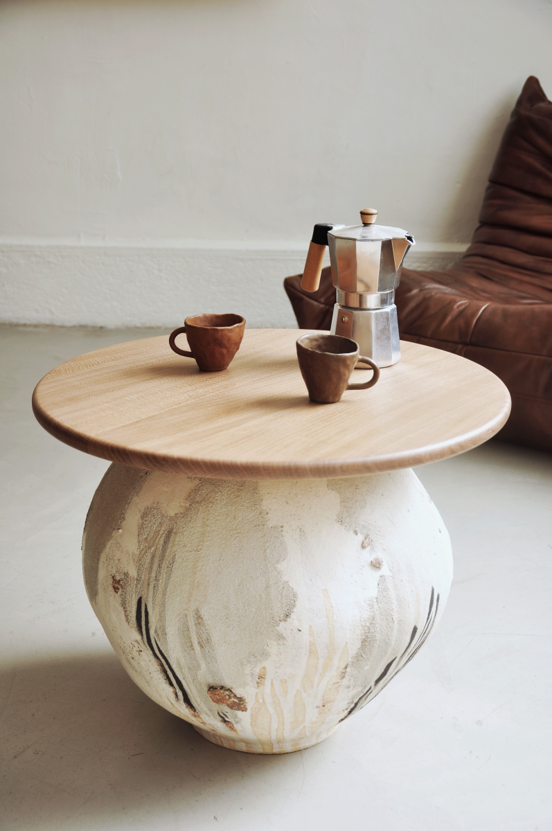 Table basse conçue et fabriquée par la céramiste Marguerite Porche. Le large piétement en grès est inspiré des jarres anciennes et parcouru d’éclats de roche glanés à Bormes-les-Mimosas. La surface du pied de cette table est travaillée de telle manière que des couches de grès, d’engobe et d’émail se superposent les unes aux autres créant ainsi un jeu  visuel et de textures sur chaque face.
