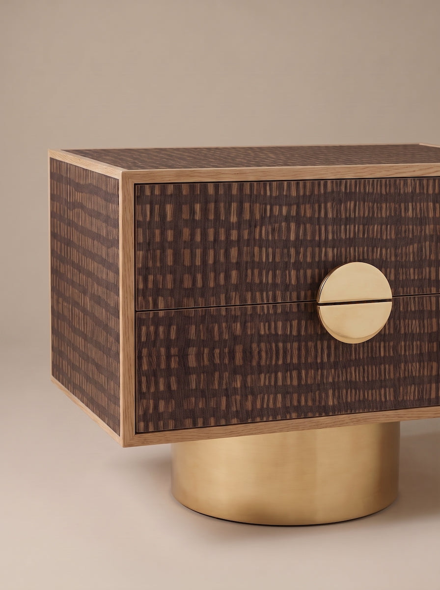 Paire de tables de chevet FAENA, imaginée par Caroline Andreoni pour la master bedroom d'une villa privée à Miami. Le caisson en chêne massif s'habille d'un placage en bois graphique aux tons ivoire et sable, posé sur un socle cylindrique en laiton poli.

Les photos affichées correspondent à la version la plus grande des chevets.