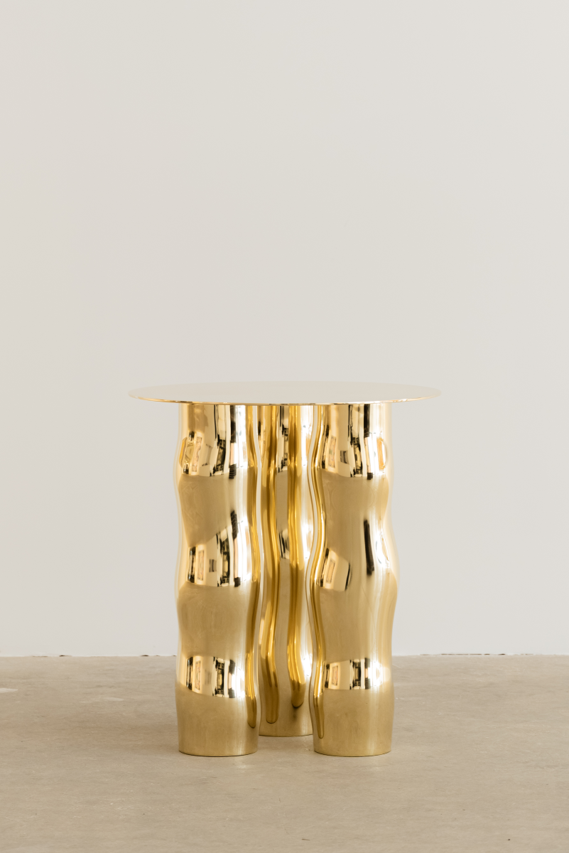 Mimo est une table d’appoint en laiton poli miroir, non verni. Sa structure repose sur une intention formelle simple : trois pieds et un plateau. Ses pieds, formés de manière organique, contrastent avec la ligne fine et délicate de son plateau.

La surface polie capte la lumière et reflète l’environnement, révélant l’élégance contenue dans la simplicité. Le laiton, travaillé à la main, invite à une expérience sensorielle où la matière et l’espace entrent en conversation.