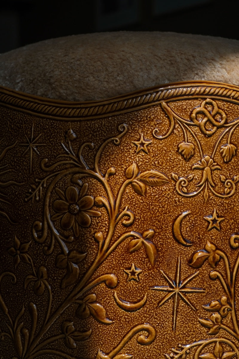 Stool Visconti by Ombre d'Or, in glazed earthenware with a Dedar fabric cushion. Its shaft engraved with alchemical frescoes draws from the Visconti-Sforza Tarot and the heritage of Cordovan leather.