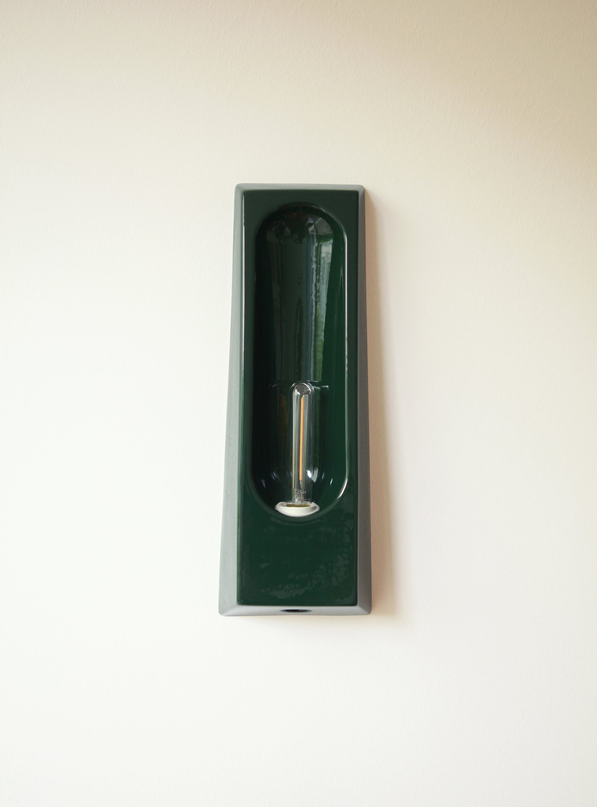 Alliance de l'artisanat et du design contemporain, les appliques Alcove de Violaine d'Harcourt sont fabriquées en céramique émaillée au Portugal, dans une région où le travail de l'argile est une tradition ancestrale. Leur forme s'inspire de l'élément architectural auquel elles ont emprunté leur nom - l'alcôve - qui évoque une ambiance intimiste et feutrée. Au centre de l'applique, une élégante ampoule tubulaire diffuse une lumière tamisée qui sublime les émaux aux teintes naturelles.&nbsp;