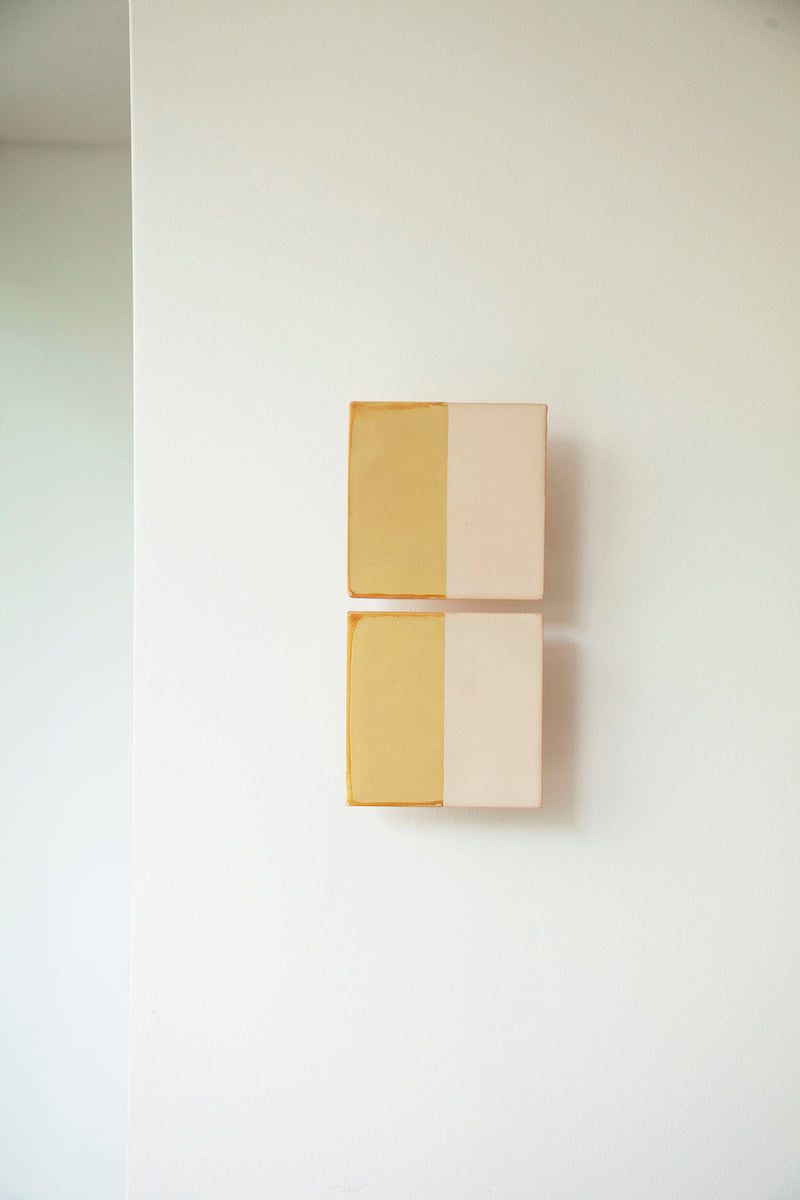 Les Tiles sont des appliques murales conçues par Violaine d'Harcourt en collaboration avec la designer hollandaise Marianne Smink. Utilisant le procédé de la sérigraphie, l'applique Tiles G est ainsi colorée d'un jaune et d'un beige représentant la céramique brute. L'ampoule, cachée derrière un carreau, diffuse un éclairage indirect, créant un effet de clair-obscur et un éclairage très doux.