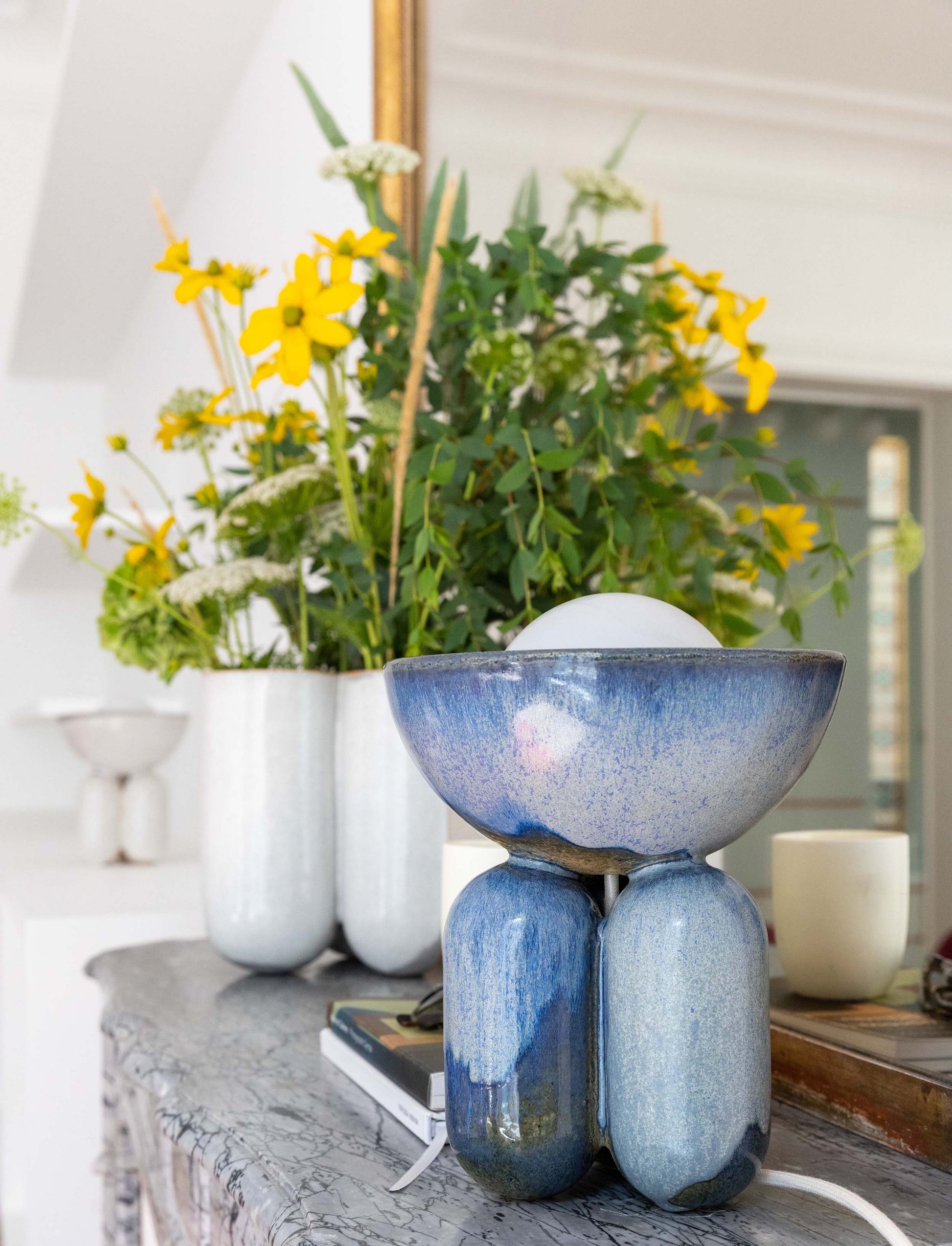 Lisa Allegra s'inspire de la forme arrondie d'une borne d'amarrage, la collection MOOR est aussi un clin d'œil à Henry MOORE, sculpteur de grands personnages se tenant souvent en équilibre dans l'espace.  Les pièces MOOR Lazuli allient un design pur et minimaliste à un émail aux nuances variées uniques. Cette association crée des objets à la fois fonctionnels et sculpturaux.