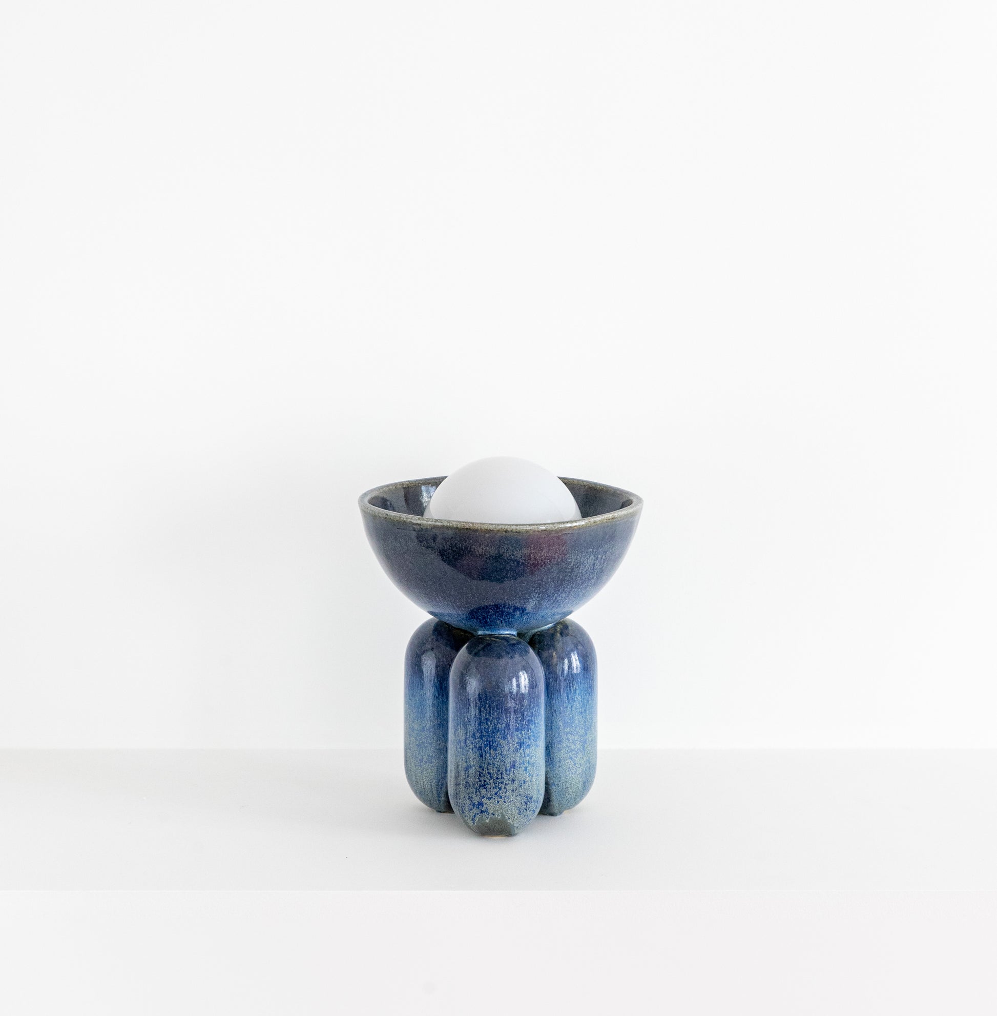 Lisa Allegra s'inspire de la forme arrondie d'une borne d'amarrage, la collection MOOR est aussi un clin d'œil à Henry MOORE, sculpteur de grands personnages se tenant souvent en équilibre dans l'espace.  Les pièces MOOR Lazuli allient un design pur et minimaliste à un émail aux nuances variées uniques. Cette association crée des objets à la fois fonctionnels et sculpturaux.